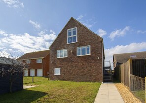 Situated in a serene grassy area, this charming building features a brick facade and a pitched roof, with a small door and two windows.