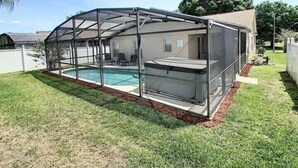 A backyard with a covered swimming pool and a house. - 4 Miles from Disney Hollywood Themed Home (Kissimmee)