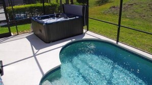 A hot tub next to a swimming pool, enclosed by a glass fence. - 4 Miles from Disney Hollywood Themed Home (Kissimmee)