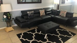 A living room with a sectional sofa, a coffee table, and a black and white patterned rug. - 4 Miles from Disney Hollywood Themed Home (Kissimmee)