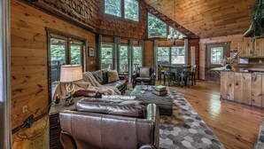 Un intérieur spacieux de chalet en bois, avec un canapé en cuir, une table à manger et un coin cuisine.