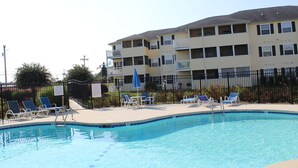 A swimming pool with lounge chairs and a multi-story building in the background. - 4106 Palms, 1st floor, 3-bedroom, 2-bath, Aug and Sept weekends still available (Rehoboth Beach)