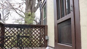 A wooden deck with a metal table and chairs, a brown door, and a tree in the background. - Charming getaway in the heart of historic Hancock Neighborhood. (Austin)