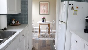 A kitchen with a white refrigerator, a sink, and a dining area with a table and chairs. - Charming getaway in the heart of historic Hancock Neighborhood. (Austin)