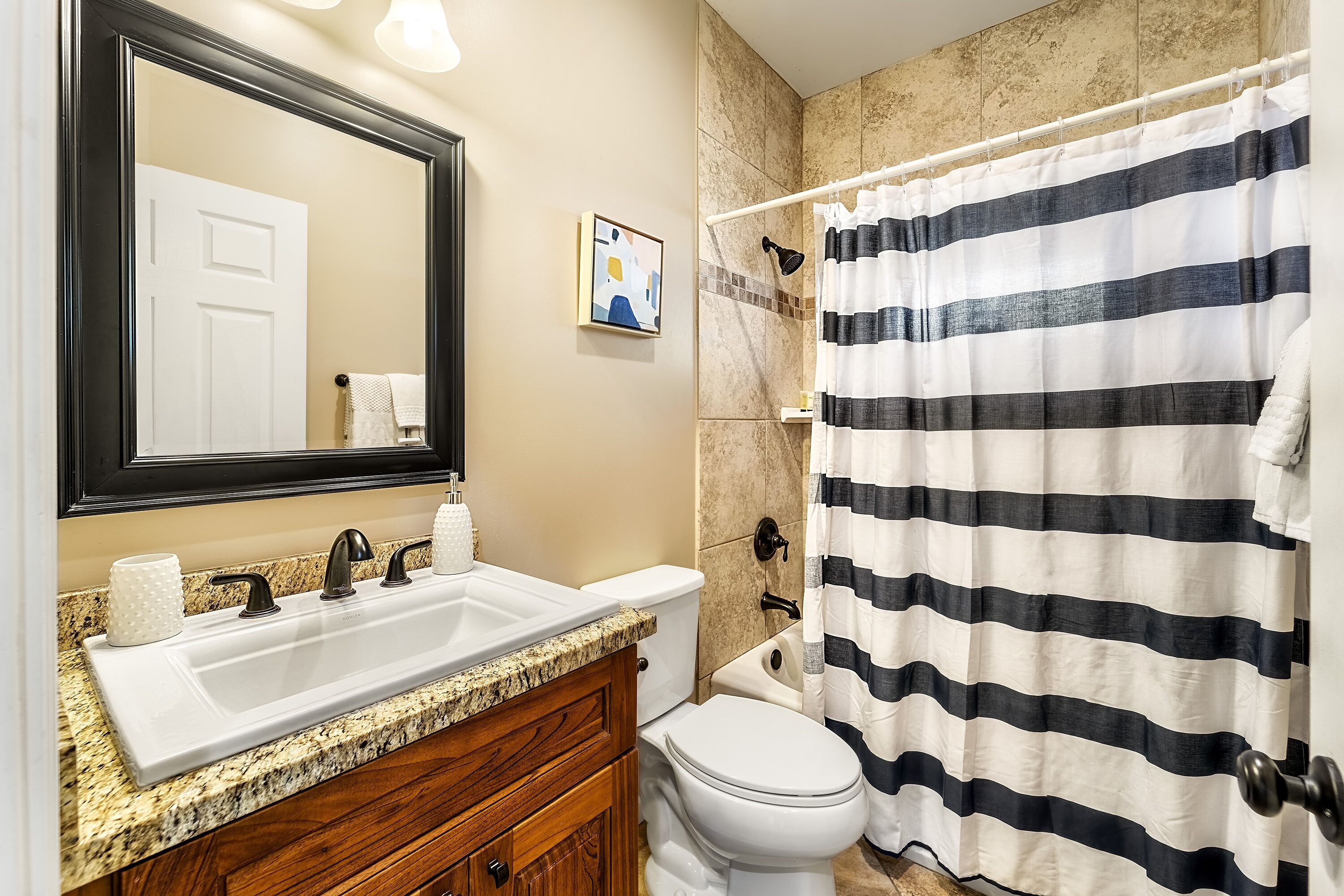 A bathroom with a white sink, a mirror, a toilet, and a shower curtain.