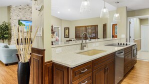 A modern kitchen with a large island, stainless steel appliances, and pendant lighting.