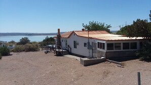 Una casa pequeña con techo de metal, un balcón y vista a un cuerpo de agua.