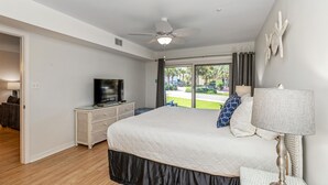 Ein Schlafzimmer mit einem Bett, einem Deckenventilator, einem Fernseher und Blick ins Freie.