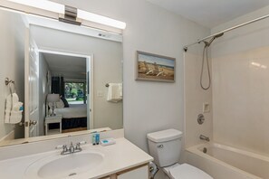 Un baño con un espejo grande, un lavabo, un inodoro y una bañera.