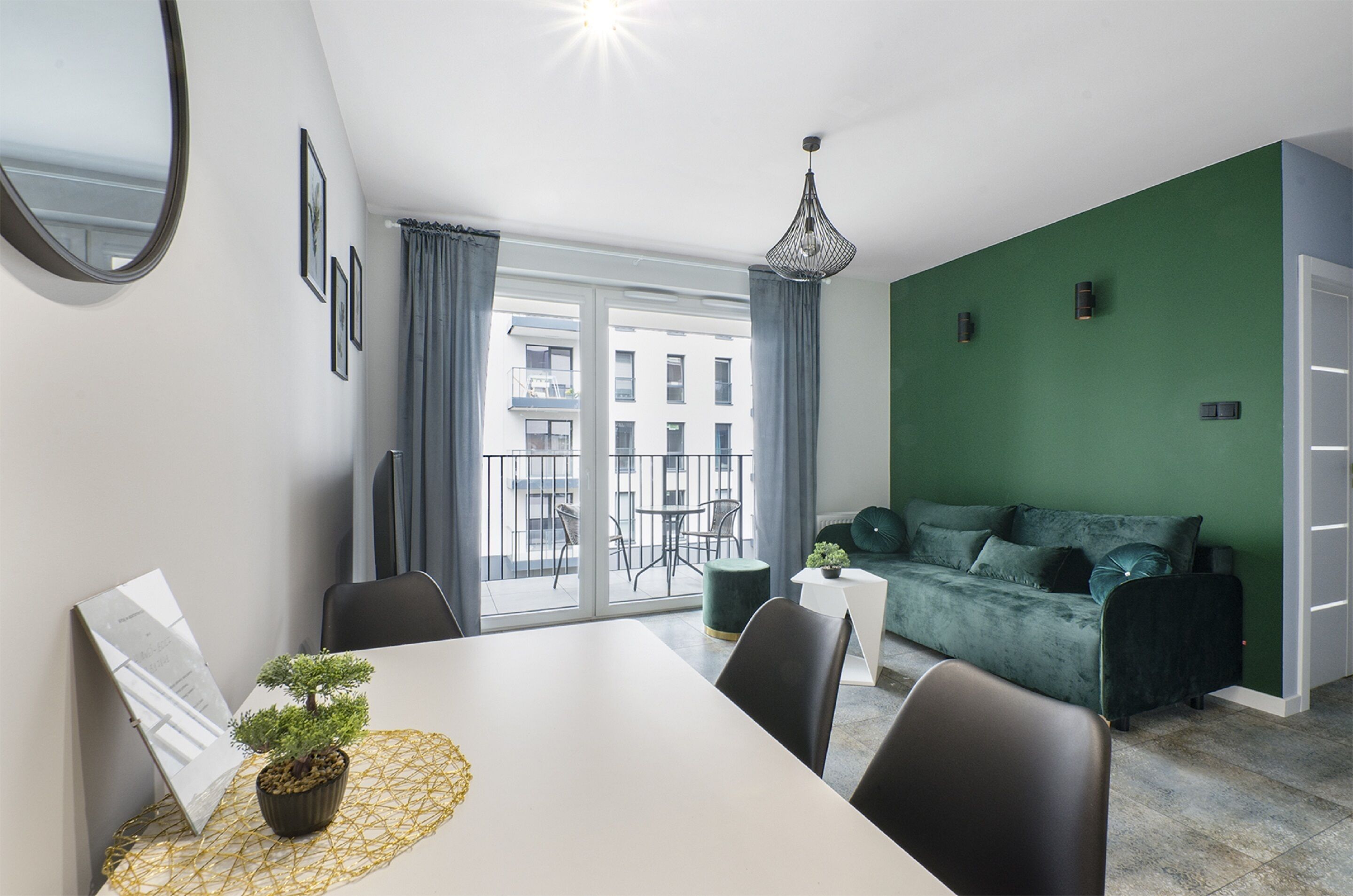 Un salón moderno con una pared verde de acento, una mesa de comedor blanca y un sofá verde.