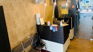 A reception area with a counter, chairs, and a door leading outside. - Hotel Lebanon INN (Tirupporur)