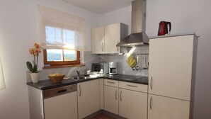 A compact kitchen with white cabinets, a dishwasher, a toaster, and a kettle on the countertop.
