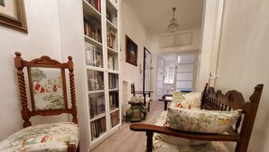 A cozy living room with a wooden chair and sofa, a bookshelf, and a framed picture on the wall.