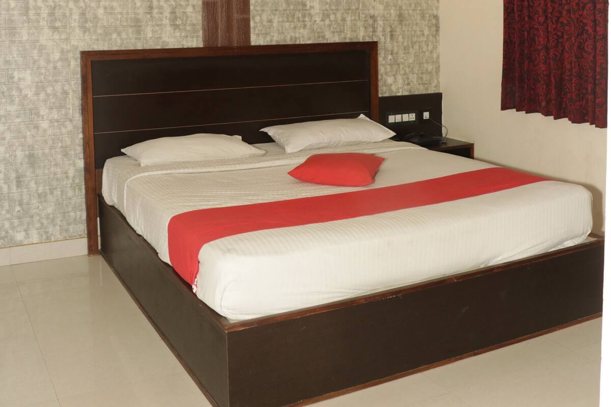 A bedroom with a bed, a ceiling fan, a nightstand, and a wall with a textured pattern.