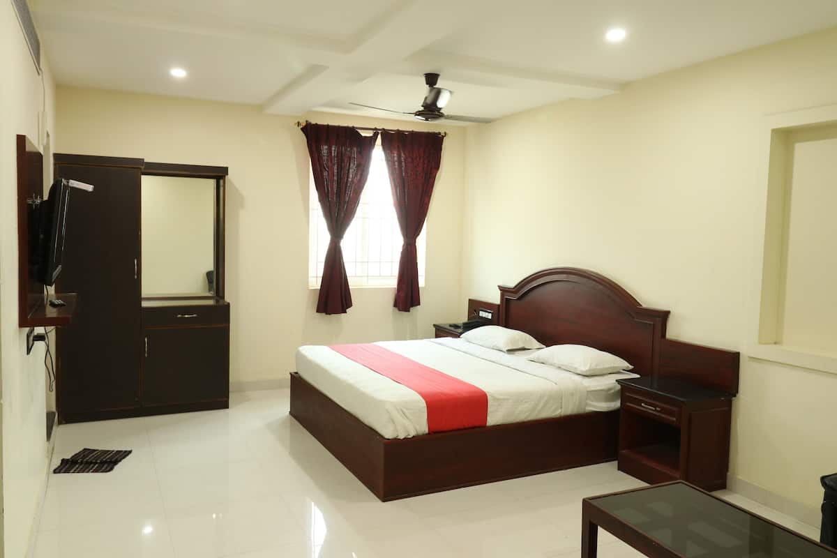 A bedroom with a bed, bedside table, nightstand, wardrobe, and a ceiling fan.