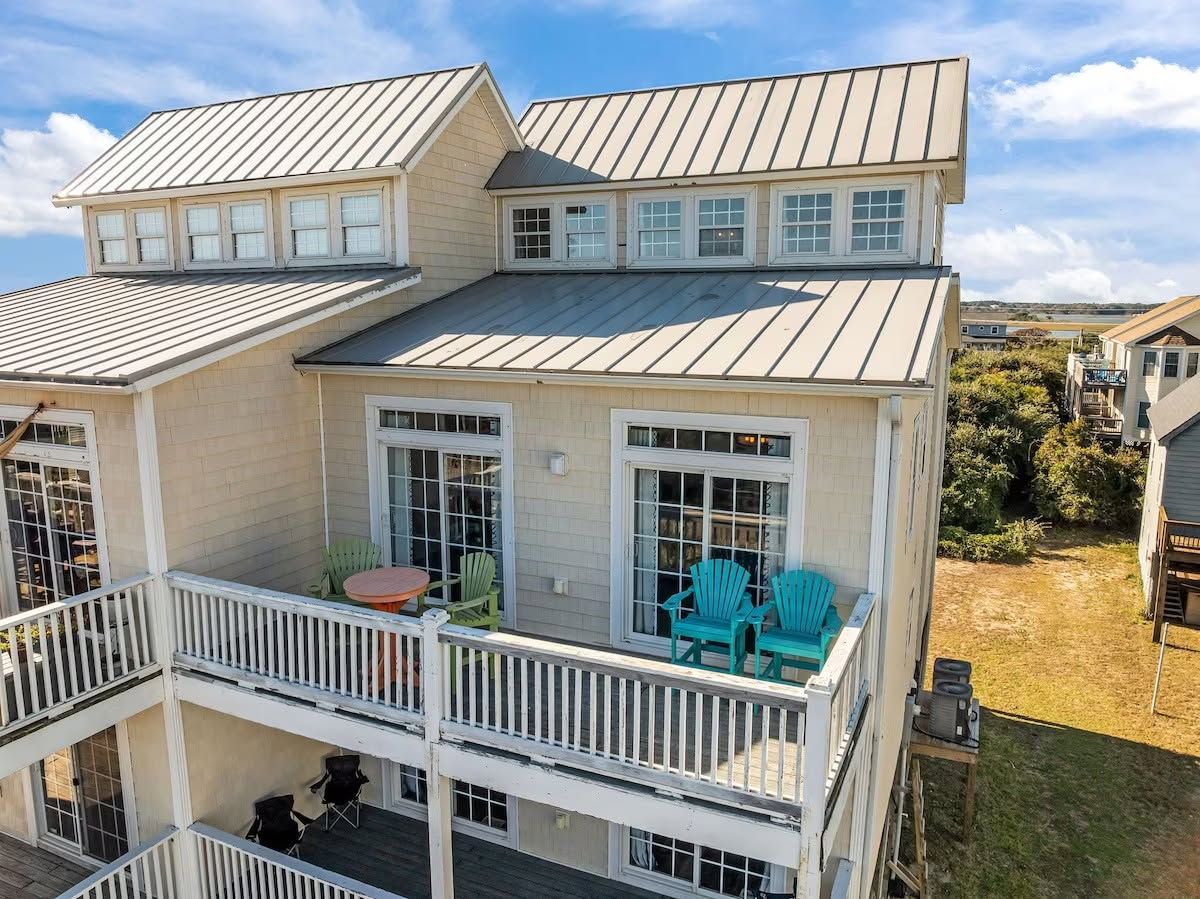 A multi-story house with a balcony, outdoor seating, and a view of the surrounding area.