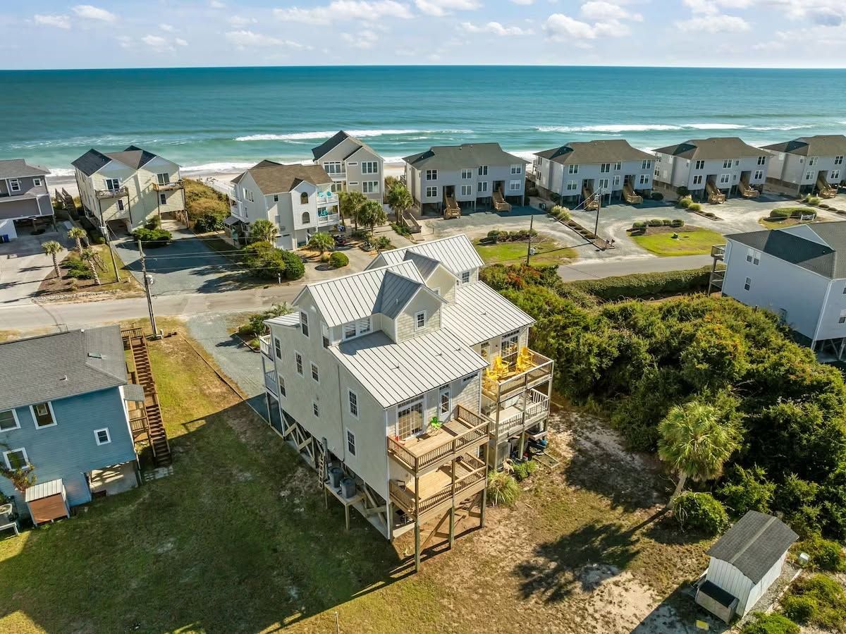 A coastal residential area with houses, a beach, and a clear sky.