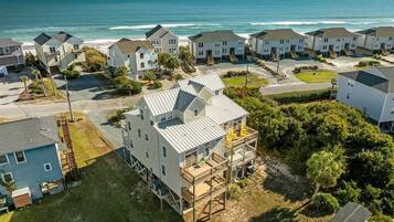 A coastal residential area with houses, a beach, and a clear sky.