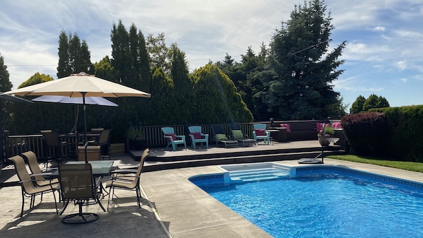 Ein Garten mit Swimmingpool, Terrassenmöbeln und einer überdachten Sitzgelegenheit.