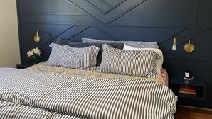 Ein Bett mit gestreifter Bettwäsche, einem dunklen Kopfteil und Nachttischlampen.