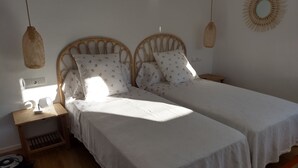 A bedroom with two single beds, a bedside table with a lamp, a power outlet, and a small rug. - Casa Margot 2 (Cadaqués)