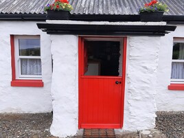 A white building with a red door and windows with red frames.