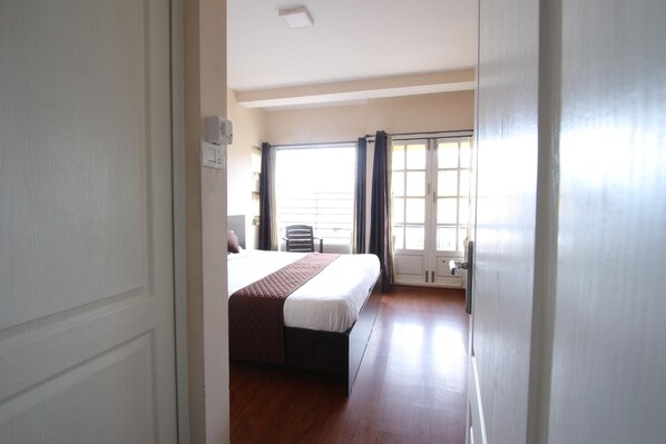 A hotel room with a bed, a chair, and a window with curtains.