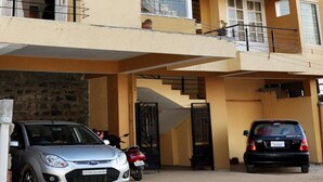 A multi-story residential building with balconies, a carport, and a garage. - The Hill Side (Ootacamund)