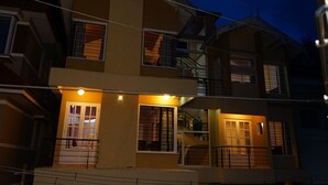 A multi-story building with balconies, staircases, and a well-lit entrance. - The Hill Side (Ootacamund)