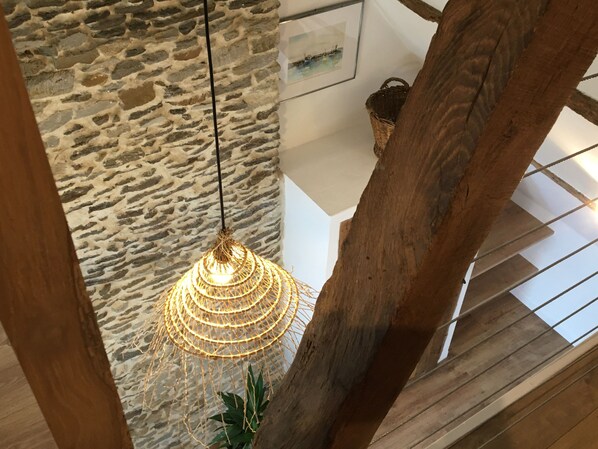 Een stenen muur, een hangende lamp en houten balken.