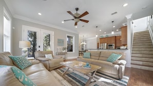 A spacious living room with leather sofas, a coffee table, and a ceiling fan. - Beach Daze New 5BR, 4BA, 16 guest, Game Room. (Destin)