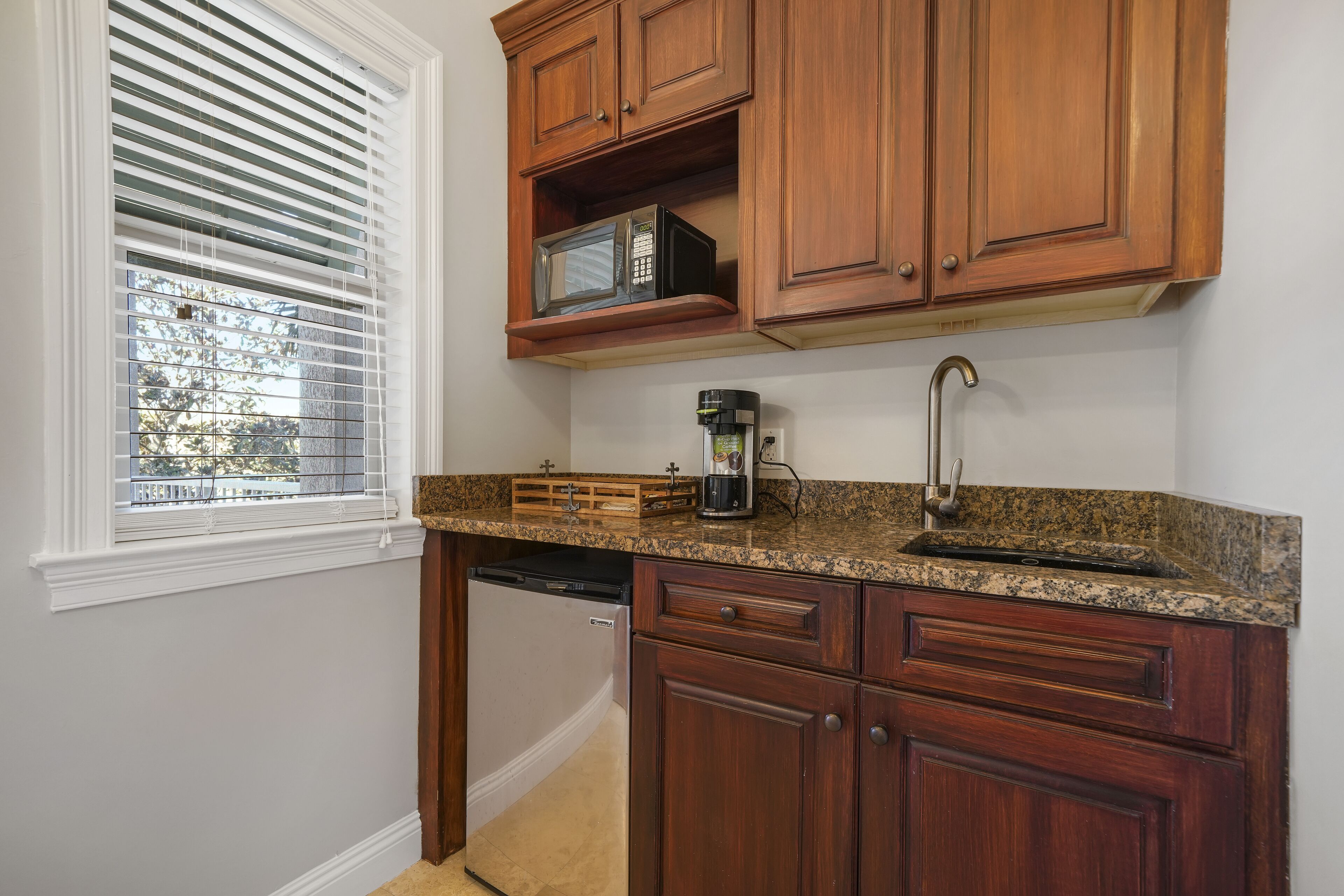 A kitchen with wooden cabinets, a built-in microwave, a coffee maker, and a dishwasher.