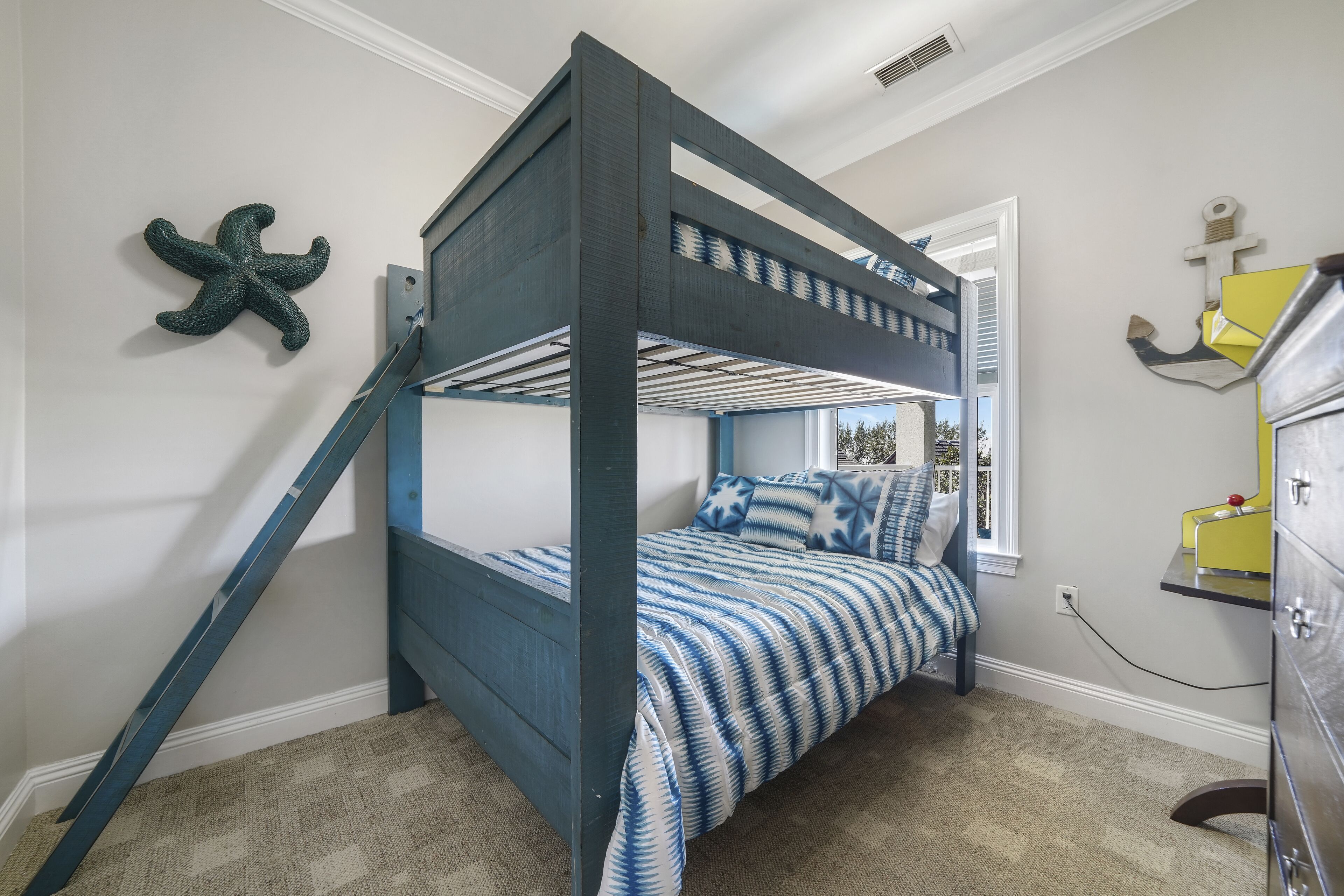 A bunk bed with a starfish decoration, a window with a view, and a dresser with a mirror.