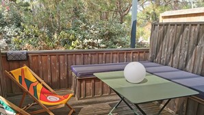 Une terrasse en bois avec une table verte, une balle blanche et une chaise colorée.
