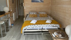 Une petite pièce comprenant un lit, une petite table, une chaise et un climatiseur fixé au mur.