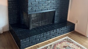 Ein Kamin mit schwarzer Ziegelgestaltung, einem hölzernen Sims und einem Spiegel darüber.