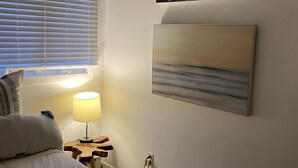 Ein Schlafzimmer mit einem Bett, einem Nachttisch mit Lampe und zwei an der Wand hängenden Bildern.