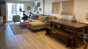 Ein Wohnzimmer mit einer Couch, einem Couchtisch, einem Esstisch und einem Laufband.