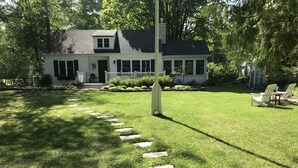 Ein Haus mit gepflegtem Rasen, einem steinernen Weg zum Eingang und einer kleinen Veranda mit Sitzgelegenheit.