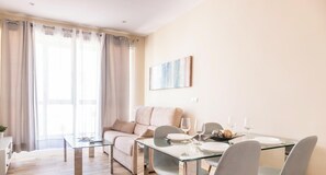 Una sala de estar moderna con un sofá, una mesa de comedor de vidrio y un cuadro en la pared.