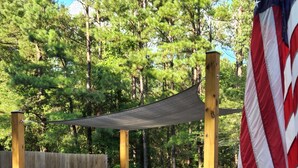 A backyard with a grill, a wooden bench, and an American flag. - Country living lake style near Santee  (Summerton)