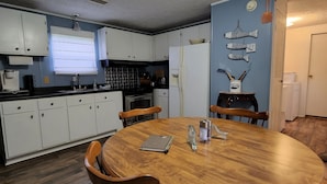A kitchen with white cabinets, a wooden dining table, and a blue accent wall. - Country living lake style near Santee  (Summerton)