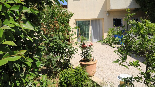 A courtyard with potted plants, a building with a window, and a door. - Appartement T2 40 M² dans villa avec jardin Semaine /WE 2 personnes (Marseille)