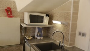A compact kitchen with a microwave, coffee maker, and sink. - Appartement T2 40 M² dans villa avec jardin Semaine /WE 2 personnes (Marseille)