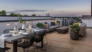 An outdoor deck with a dining table set, seating, and a fire feature. - Casa Paradisa • Rooftop, Fire Pit, Skyline Views (Nashville)