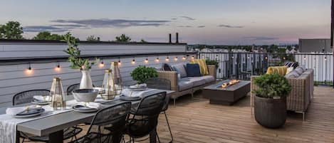 Terraza exterior con mesa de comedor, asientos y una chimenea.