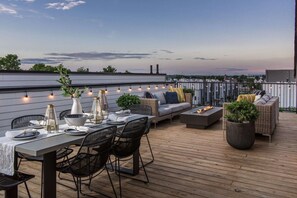 An outdoor deck with a dining table set, seating, and a fire feature. - Casa Paradisa • Rooftop, Fire Pit, Skyline Views (Nashville)