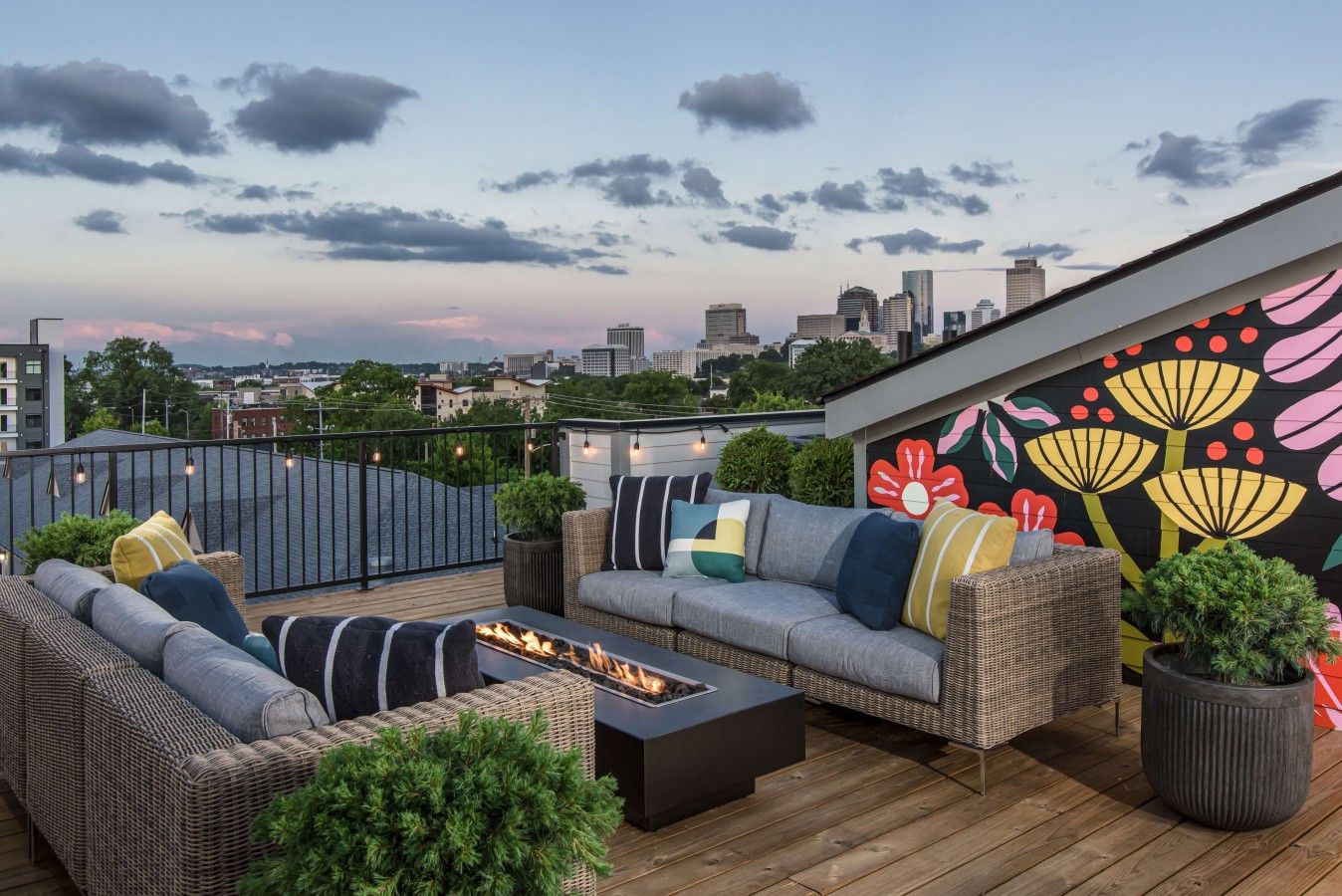 A rooftop terrace with outdoor seating, a fire feature, and a colorful mural.