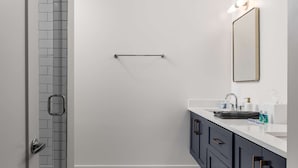 A modern bathroom with a shower, a sink, and a mirror. - Casa Paradisa • Rooftop, Fire Pit, Skyline Views (Nashville)