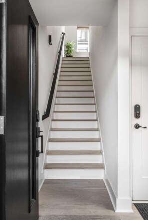 A staircase with a handrail, a door with a handle, and a small window at the top. - Casa Paradisa • Rooftop, Fire Pit, Skyline Views (Nashville)